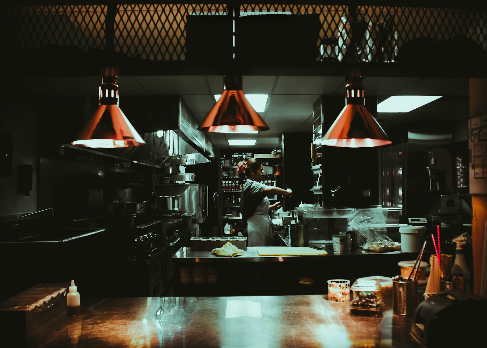 commercial-kitchen-layout-design-for-restaurants-thumbnail woman standing near three red pendant lamps